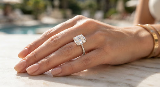 Anillo de diamante talla cojín sobre una mano cuidada a la luz del sol