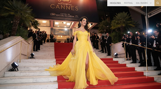 Actriz bajando una escalinata de mármol con un vestido amarillo de alta costura